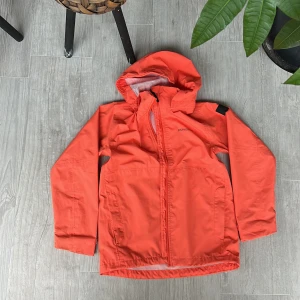 Regnjacka - Orange regnjacka från Didriksson i perfekt skick. Använt 1 gång. 100% vattentät. Avtagbar luva.  Storlek 150. Pris 200kr