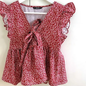Röd blommig topp - Söt sommartopp med knytning! Älskar passformen och mönstret. Perfekt nu på sommaren både till fest och vardags 😍Säljer för endast 120 kr!