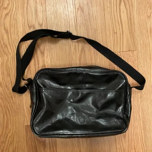 Svart adidas axelremsväska - ANVÄND INTE KÖP DIREKT!!💞 Säljer denna svarta adidas axelremsväska / skolväska! Lite sliten (bild 3, ser ut så på alla nedre hörn) men det är inget man tänker på. 