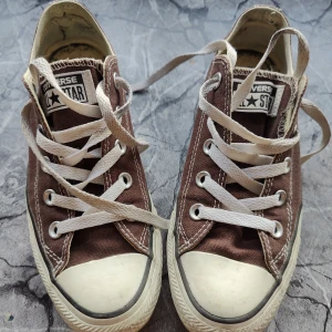 Converse  - Bruna och vita låga Converse, storlek 36,5. 23 cm. Fina icke-slitna sulor och tyg. Lite missfärgningar som nog går att tvätta bort på sidorna av sulorna. Fula inuti då jag haft en inläggssula i dem, men den syns inte om man lägger i en tunn innersula.