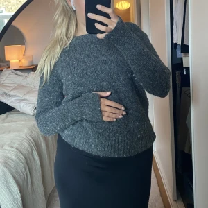 Mörkgrå stickad tröja  - Har slits vid ärmsluten. 