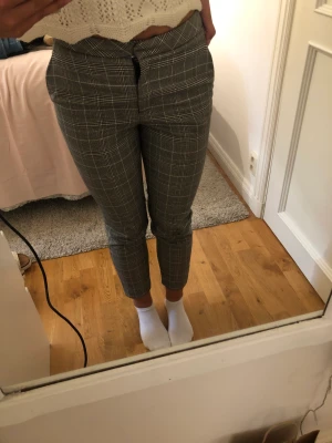Kostymbyxor  - Ett par rutiga kostymbyxor i grå. Går till anklarna på mig som är 161 cm lång. Har inga bakfickor men har framfickor. 
