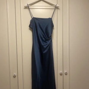 Satinklänning - Blå klänning med slit i satin från Zara, går till vaderna. Använd en gång. Några små defekter i sömmarna men som inte syns om man inte kollar noga.   Köparen står för fraktpriser, jag ansvarar inte för postens slarv.  Storlek S 