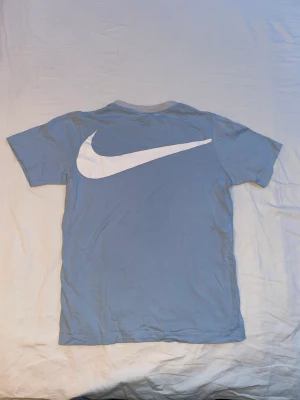Babyblue Nike T-shirt  - Säljer en babyblue tröja från Nike i storlek 147-158 med en liten fläck på ryggen.   Kolla i min profil för liknande plagg😉