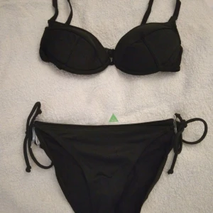 Svart enkel  bikini, överdel+underdel. Strlk: 34/XS. Felfri. - Svart enkel  bikini, överdel+underdel.  Strlk: 34/XS. Felfri. Överdelen är 70A/XS med pushup, knäpps i ryggen, och nederdelen är 34/XS ned knyt i sidorna. Frakt tillkommer. OBS! BUDA EJ OM DU INTE TÄNKT BETALA. Oseriösa anmäls och blockeras direkt.
