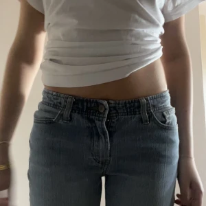 Lågmidjade flare jeans  - Super snygga lådmidjade, ljusblåa jeans med tunna vita ränder. I ny skick och bara använda 2 gånger. Passar mig som har storlek S eller 26x32