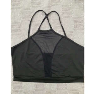 Svart top genomskinlig band - En supersnygg top med band som korsar varandra över ryggen. Aldrig använd. Passar en M. Mått:  Armhåla-armhåla: 42 cm. Längd: 30 cm.  Finns att hämtas i Stockholm. Hör av dig om du har någon fundering!