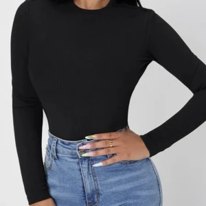 Svart Tröja - En svart långärmad tröja i ett ribbat material med en liten tutle neck. Plagget är mycket liten i storleken den passar bra för storlek S-M trots att det är en XL. 