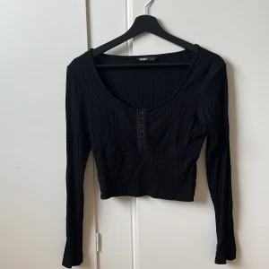 Topp - Lite kortare topp med knäppning vid bröstet. Storlek M.