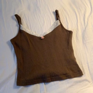 Brunt linne - Brunt linne i storlek XS med vit spets och en rosa blomma längst fram🌸Köpt på pimkie i Frankrike.