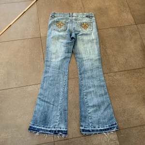 Ljusblåa lågmidjade bootcut jeans  - Lågmidjade bootcut jeans med mönster på bakfickorna🫶perfekt till sommarn, tyvärr för långa på mig som är 160 innebenslängden är 90cm å midjemåttet är 43cm rakt över🤝kontakta om du vill använda köp nu