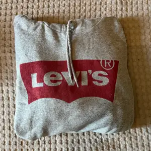Grå Levis hoodie med tryck i fram. Använt skick men inga märken, fläckar eller hål osv. Storlek Large   Finns i Vallentuna! Köpare står för frakt!
