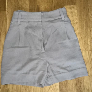 Dress Shorts - Gråa/khaki frestade shorts från H&M. Dom passar perfekt med en vit blus nu på sommaren. Säljer pga att de inte passar längre 💕
