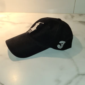 Polo keps Ralph Lauren i svart, justerbar baktill.  - Svart Ralph Lauren keps i stl medium men ändå justerbar baktill med kardborre fäste.