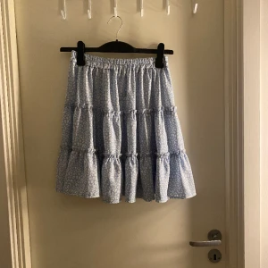 Kjol - Blå kjol med vitt leopardmönster, använd 1 gång och är nyskick. Bra längd.