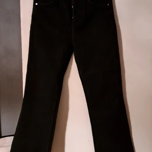 Coola svarta Bootflare jeans - Riktigt tuffa coola svarta jeans som är boot-flare i benen. Benen är klippta längst ner,men inte av mig,de var så vid köp.. De är högmidja.Storlek 30 i midjan och 32 i längd.Säljer då de är för stor i midjan.
