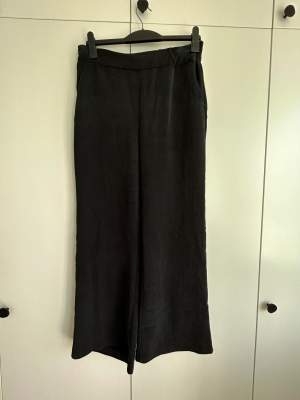 Wide, loose pants in black “matte” fabric. Pockets. 