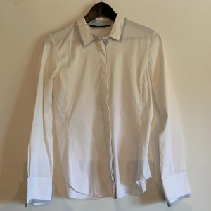 Vit skjorta - Vit skjorta från Zara med blåvit-randiga detaljer. Figursydd så trots att den är märkt som en M är den mer åt S-XS hållet. 