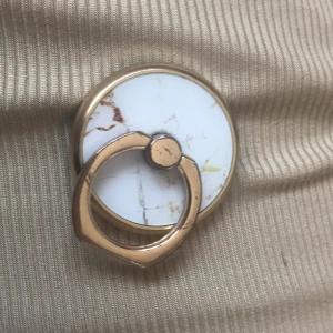 Guldig mobilhållare - Säljer denna ”mobilhållare” pga kommer inte till användning. Lite repigt på ”ringen” som man har på fingret. Annars inget täcken på slitage,💅🏼📱 Den är magnetiskt så funkar bara på magnetiska skal. Org pris 249 kr