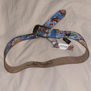 Ed Hardy bälte med fina detaljer - Oanvänt bälte från Ed Hardy med autentiseringstag kvar. Bältet är ca 100cm långt mätt utan spännet. Skriv för frågor eller fler bilder på detaljerna. Kan mötas upp i Malmö. Pris kan såklart diskuteras bara skriv