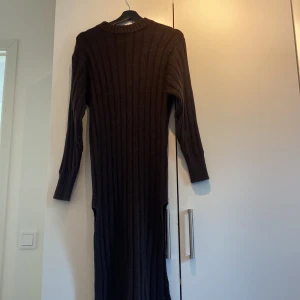Stickad klänning - En brun fin stickad klänning med slits på båda sidorna, börjar bli lite nopprig på underarmarna.