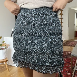 Blommig kjol - Tajt trikåkjol, svart med ljusblåa blommor! Använd fåtal gånger!