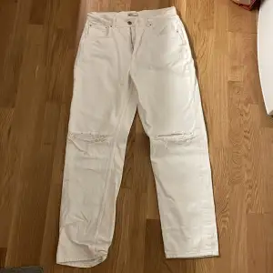 Vita jeans med hål i båda knäna
