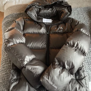 Calvin Klein vinterjacka  - Calvin Klein vinter/ dunjacka i grå brun färg.  Väldigt fint skick på jackan. Jag säljer den för 600kr nypris 2195kr. Storlek S  Kan mötas upp i Jönköping annars står ni för frakt själva