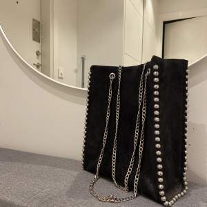 En svart lite större väska från Zara med silverdetaljer! Ett större fack med dragkedja i mitten och sedan ett mindre på sidan. Perfekt till skola/jobb!🌸Knappt använd! 