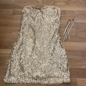 Guldig paljettklänning  - Helt ny klänning, helt oanvänd! Band följer även med.  Klänningen är i XS, men skulle nog säga att den passar någon som har storlek S också.
