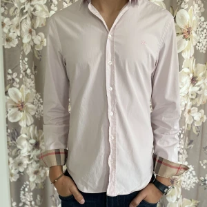 Burberry Skjorta - Säljer en riktig snygg ljus rosa Burberry skjorta. grymt skick och har inga defekter. Storlek S men passar även XS och M. modellen är 182 cm lång. Bara att skriva ifall ni har någon fråga!