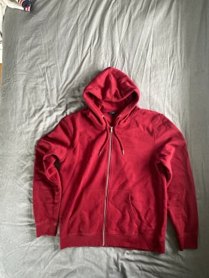 Röd zip hoodie - Säljer nu en röd zip hoodie! Är en hoodie som har kommit till användning ibland men inte så mycket då den känns lite för stor för en! Är i storlek L men skulle nog passa lika bra i XL. Köpte den för 1 år sen ungefär och har varit använd lite mellanåt! 
