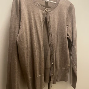 Kofta lindex - Beige kofya med guldiga knappar, aldrig använt. Storlek M men rätt stor. 