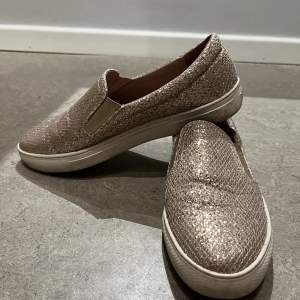 Guldiga och glittriga sneakers / loafers från Dasia i storlek 38. Superbra skick, använda ett fåtal gånger. 