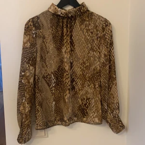Blus strl 36 - Tunnare mönstrad blus från H&M i storlek 36. Krage som går upp lite över halsen och knäpps med två knappar i nacken (bild 2). Fint skick! Kan mötas upp i Linköping annars står köparen för frakt. Katt i hemmet 😸