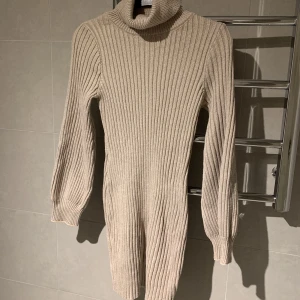 Stickad klänning - Superfin stickad klänning med turtleneck! Oanvänd, säljes då den ej kommer till användning… storlek 34/36  men passar 38 också. Kall Beige/brun färg