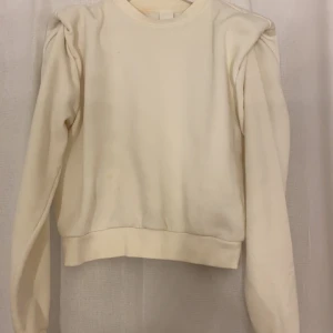Vit tröja - En vit tröja men kuddar på axlarna. Använd en gång. Storlek s och kommer från H&M. Tre små fläckar fram men inte så synliga.