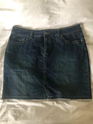 Jeanskjol 46 - Mörkblå jeanskjol i storlek 46, från Kappahl. Midja: 100cm. Längd: 48cm. Finns inga bilder på men Dma gärna vid andra frågor eller funderingar. Köparen står för frakt.