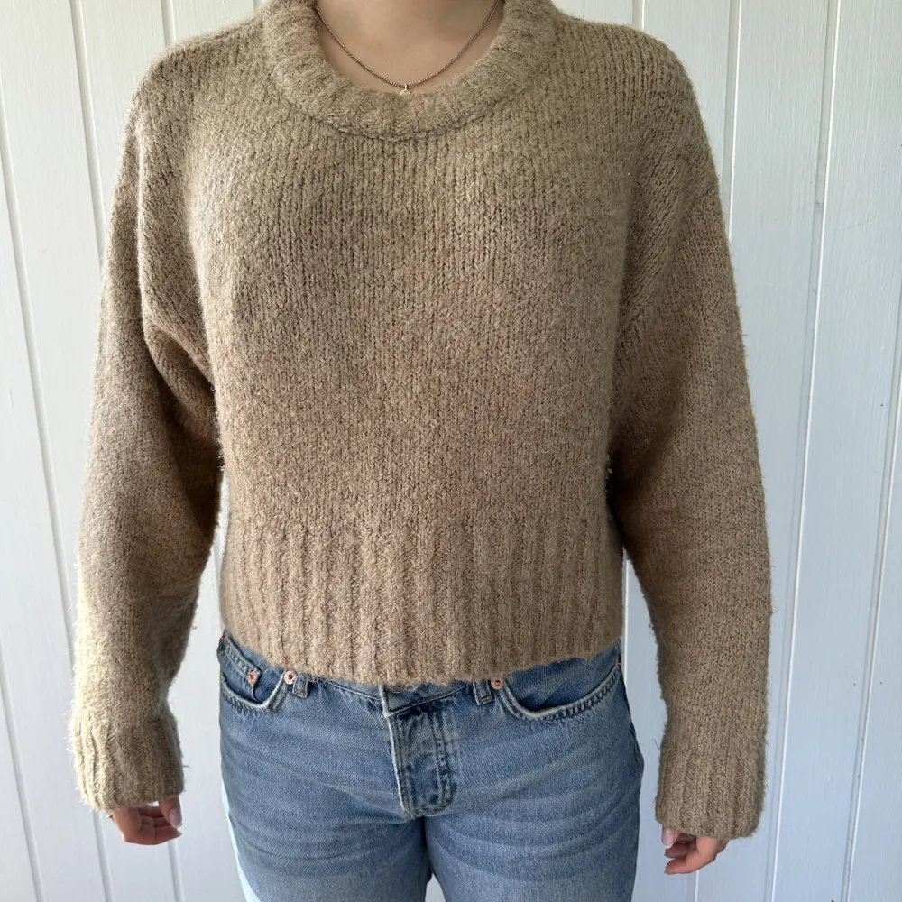 En beige/brun stickad sweater som är lite mot det croppad håller. Supersnygg och enkel att styla. . Stickat.