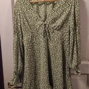 Grön mönstrad klänning - Grön mönstrad klänning med volenger nertill och vid armarna från Asos. Normal i storleken!