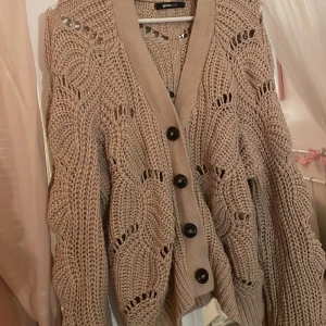 Virkad cardigan - Virkad cardigan beige / smutsrosa färg med bruna knappar. Storlek L & passar perfekt till någon med storlek L eller någon som vill ha en lite mer oversized look 💕