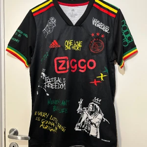 Bob Marley X Ajax fotbollströja  - Svart Bob Marley X Ajax fotbollströja med massa olika ikoniska Bob Marley citat. Helt ny i storlek S.