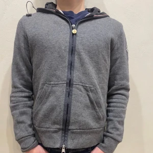 Moncler zip up hoodie/cardigan  - Tjena, Säljer nu en moncler cardigan/zip up hoodie det är någon slags blandning. Skick 9/10 det ända är att en liten tråd har låsbar se bild 3. Självklart äkta. Vid frågor och funderingar skriv gärna🙌🤝.