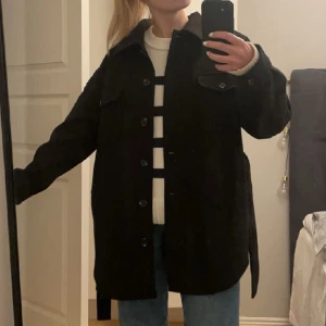 Svart kappa!  - Svart kappa med knappar och band runt midjan. Köpt från Nelly! 