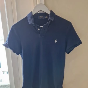 Blå Ralph luren pike - Vi säljer en blå Ralph lauren piké för ett väldigt bra pris. Vi har tyvärr bara 1 bild för att vi itne har tid att ta fler bilder just nu men de är bara att fråga ifall det är något:)