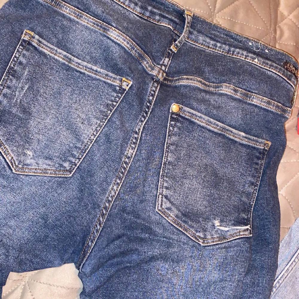 Blåa jeans med hål i knäna och ”slitningar” vid bakfickorna och midjan. Använda fåtal gånger så inga slitage från användning eller noppror.. Jeans & Byxor.