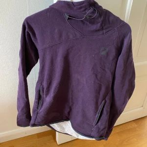Klättermusen hoodie - Härlig hoodie från Klättermusen, den har luva och relativt hög krage vilket gör den perfekt för skidåkning/kallare väder. Den har också öglor i ärmarna som man kan sätta fast tummarna i, se bild 2.   Älskar den men har för många hoodies…
