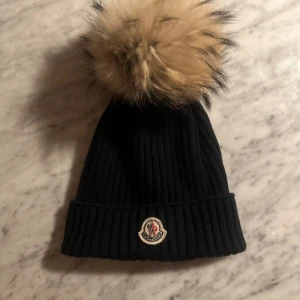 Moncler mössa - Jätte fin mössa från moncler, fåtal gånger använd, ny pris ca 2000. Marin blå och äkta päls, prefekt nu till vintern❤️