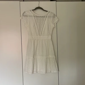 Vit klänning - Den här superfina vita klänningen har ett väldigt fint mönster och är öppen i ryggen.  Den har en osynlig dragkedja i ena sidan och har ett undertyg vilket gör att den inte känns genomskinlig. Köpte den till studenten för den är SÅ fin men valde en annan.