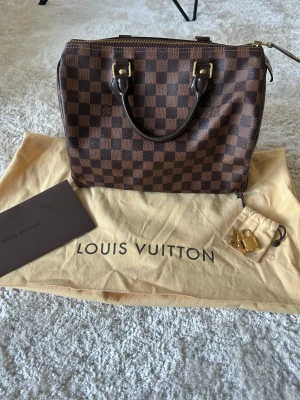 Louis Vuitton Speedy damier 30 - En väl omhändertagen Louis Vuitton Speedy damier 30 väska som ökar i pris varje år. Väskan är i fint skick, dock lite slitage på utsidan samt mindre fläck på insidan (skickar bilder vid intresse). Med väskan medföljer kvitto, dustbag, lås och nyckel. 